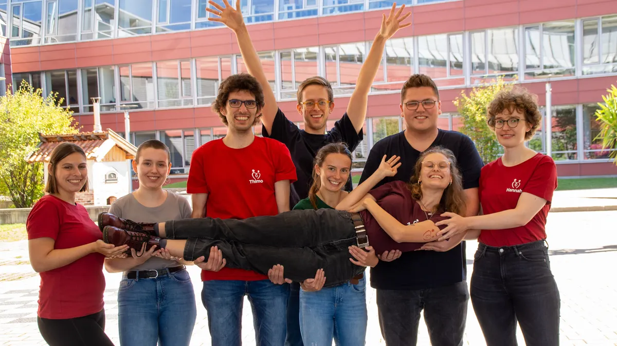 Ehrenamtliche zeigen sich vor einer Schule.