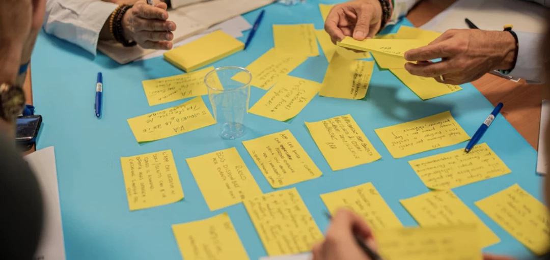 Menschen sammeln Ideen auf gelben Post-It Notizzetteln 