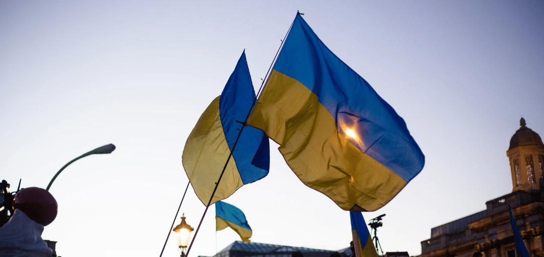 Zwei Ukraine Flaggen im Himmel über demonstrierenden Menschen 
