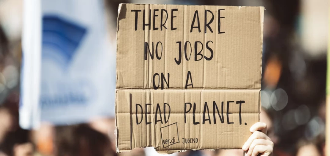 Hand hält ein Schild aus Pappe hoch "Es gibt keine jobs auf einem toten Planeten" 