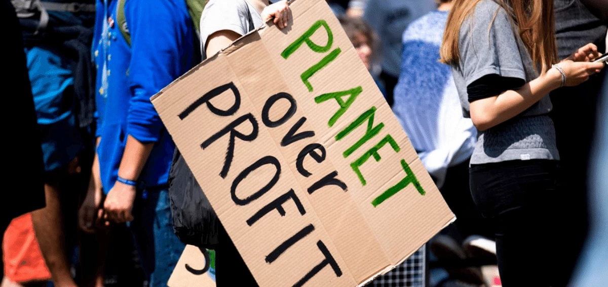 Menschen die ein Pappschild mit Aufschrift 'Planet over Profit' halten 