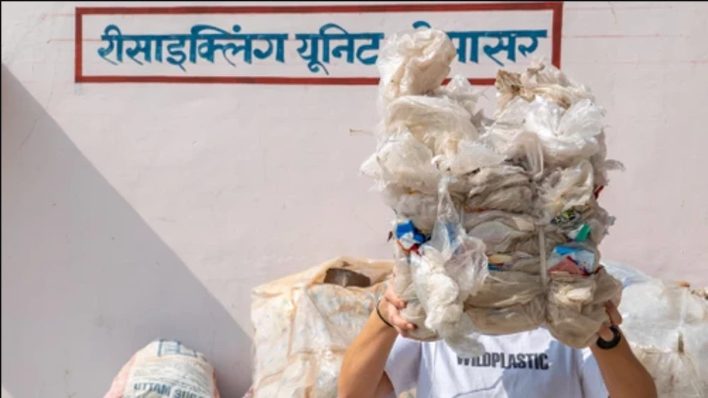 Eine Person hält gesammelten Plastikmüll in die Kamera