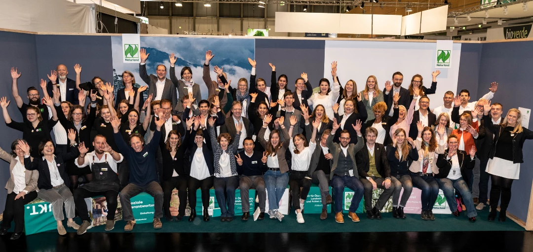 Teamfoto von Naturland auf der Biofach Messe 2020 - Personen streckend jubelnd die Arme in die Luft 