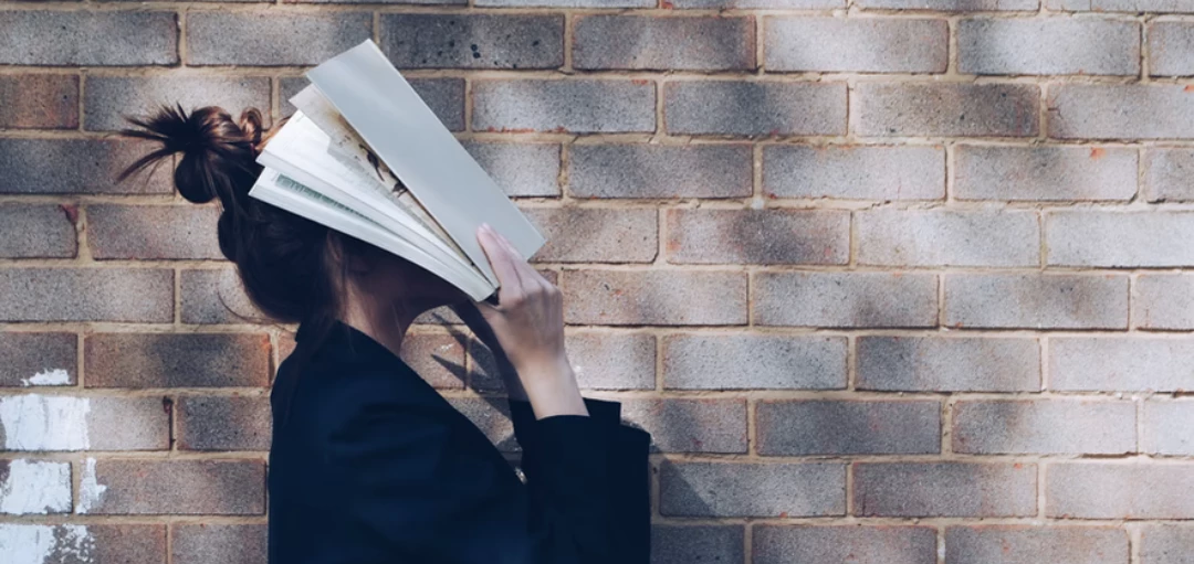 Person vor einer Steinmauer mit Buch im Gesicht, Verzweiflung 