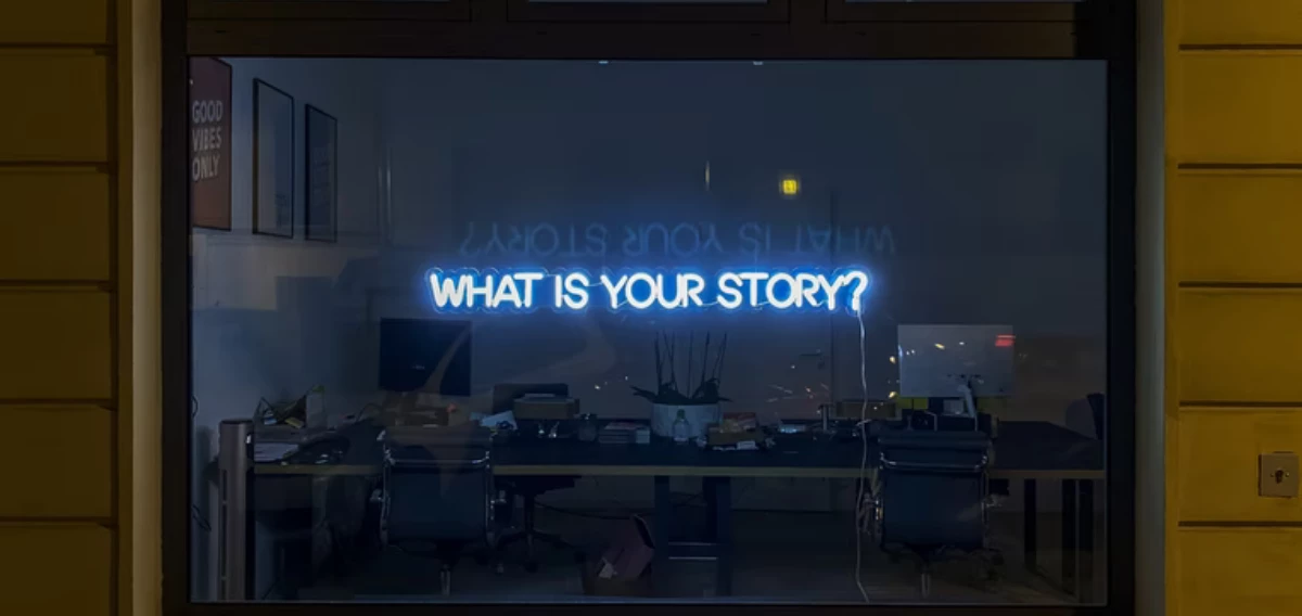 Blaue Leuchtschrift "What is your story?" in einem Schaufenster 