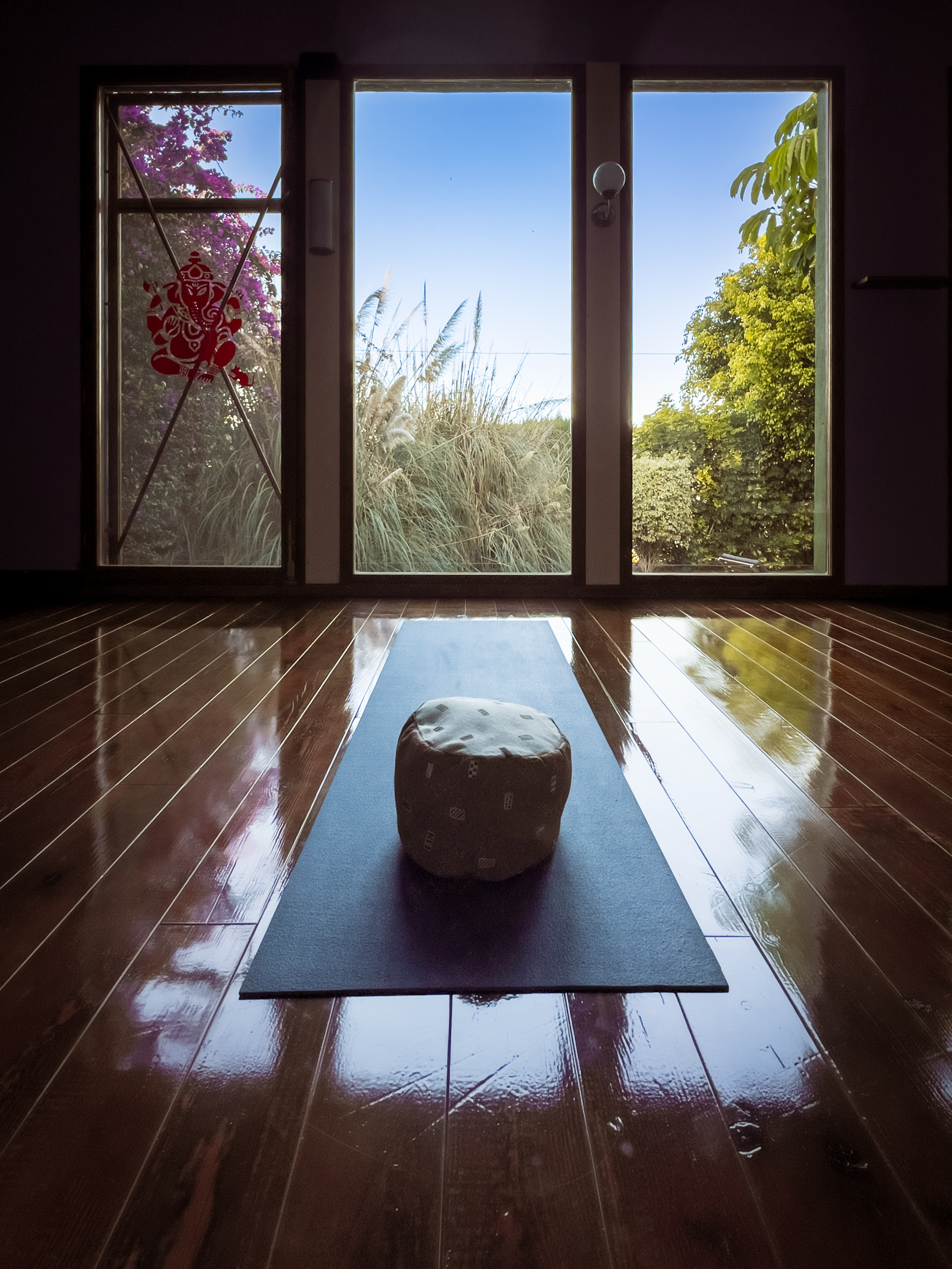 Yogaraum mit Blick aus dem Fenster. In der Mitte liegt ein Yoga Pouff